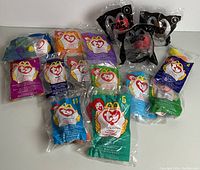 Photo showing all 13 sealed McDonald's Happy Meal toys including TY Beanie Babies and Star Wars plush figures.