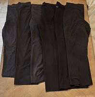 Six pairs of black women's plus size pants arranged flat on surface