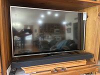 Samsung 40-inch TV placed inside a wooden cabinet, showing the full front view with TV and soundbar.
