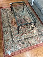Area rug laid on hardwood floor with a glass coffee table on top. Shows the full size and overall pattern of the rug.