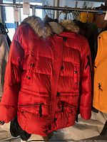 Red women's puffer coat by Eddie Bauer with quilted design and fur-trimmed hood hanging on rack alongside other jackets.
