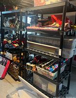 Full side view of 4-tier black plastic shelving unit with various items stored on shelves, showing structure and material.