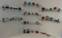 Corner view of wall-mounted glass shelves displaying paperweights, decorative glass items and two metal trays