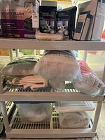 View of rack with velvet plush heated blanket, mattress protectors, pillow forms, and packaged sheet sets