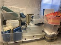 Wide view of the multitudes of plastic storage bins and totes in different sizes and colors stacked near a wall and window with natural light.