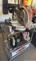 Full view of metal wire cart with Skil circular miter saw on top and other tools underneath