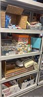 Full view of shelving rack with boxes, fabric pieces, and plastic storage containing quilting and sewing supplies.