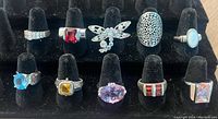 Photo showing ten rings in a black velvet ring holder, displaying variety of designs and stones.