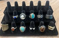 Photo of a black display holding 11 sterling silver rings including different stones and designs