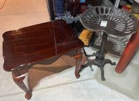 Photo showing one wooden side table and vintage metal tractor seat stool in basement