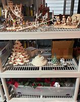 Full view of three shelves showing mixed Christmas decorations including the ceramic Christmas trees and a white branch.