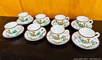 Eight Villeroy and Boch Botanica pattern cups paired with matching saucers, arranged on a table showing details of the design and overall condition.