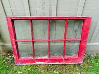 Front view of red painted wooden antique window with eight glass panes.