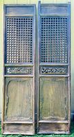 Full front view of both carved Chinese garden gate doors showing lattice work, carved panels, and wood grain.