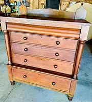Full front view of antique cherry wood tallboy dresser showing four drawers and turned columns beside the drawers.
