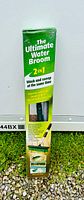Original green box of The Ultimate Water Broom showing 2-in-1 wash and sweep functionality, with text highlighting stiff bristles and high pressure spray jets.