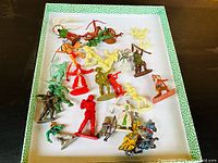 Overview of various vintage plastic figures including cowboys, soldiers, archers, and some diecast knights on horseback.