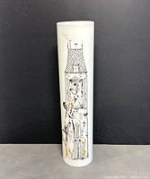 Front view of the tall cylindrical white porcelain vase with black and gold artistic design of a house with two characters.