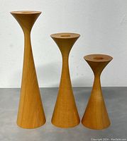 Side view of three handcrafted wood candle holders of varying heights with smooth wood grain finish.