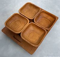 Set of four square teak bowls sitting on a rectangular teak serving tray with visible wood grain.