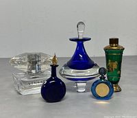 Group photo of four vintage glass perfume bottles showing various shapes and materials.