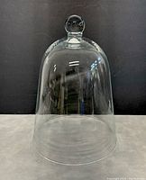 Front view of clear glass cloche bell dome cover showing full shape and top knob detail.