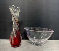 Hand blown red and clear glass vase with finger design next to Lenox clear glass candy bowl with pink rim, both items side by side.