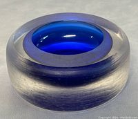 Close-up front view of the round art glass bowl showing deep blue inner core blending to translucent smoky outer layer with smooth finish and minor wear.