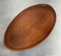 Top view of oval teak tray showing interior surface and gentle raised edges with integrated handles.
