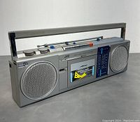Front view of the silver JVC Biphonic RC-S40C boombox showing two large speakers, cassette compartment with Biphonic label, radio tuner display and control buttons with metal handle.