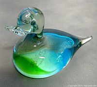 Photo of signed Chalet art glass duck paperweight showing front and side views with blue and green colors and clear glass head and beak.