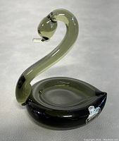 Full view of the vintage glass swan paperweight with curved neck and round base shaped as shallow bowl.