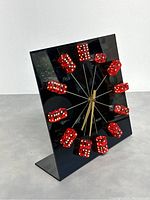 Front angle of vintage Las Vegas dice clock showing black face with twelve red dice hour markers mounted on rods.
