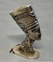 Side angle view of the silver bust paperweight showing detailed profile and headdress of Queen Nefertiti.