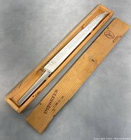 Photo of the 17-inch steel cutting blade in its wooden case, showing the blade and case fully.