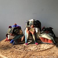 Photo showing three children's hats and three pairs of shoes positioned on a carved wooden table, illustrating overall lot contents and condition.