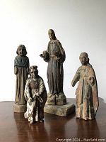 Group shot of four carved wood Santos figures on tabletop