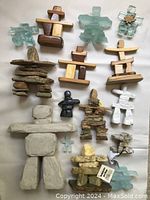 Photo showing full collection of 14 Inuit inuksuit souvenirs made of wood, stone, and fused glass. Includes a ruler for scale.
