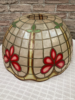 Side view showing domed shape, cream Capiz shell panels, pink five-petal flowers and green bamboo leaves framed in patinated metal.