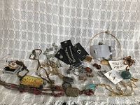 Full lot on white lace background showing mix of necklaces, brooch, earrings, pendants, and bracelets.