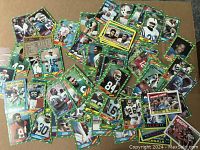 Selection of vintage football cards laid out, showing diverse players and teams with green border design, some cards stuck together and worn.