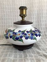 Front view of the vintage round ceramic lamp showing blue enamel floral design and wooden base.