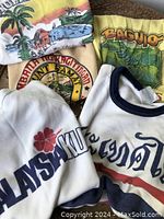 Four tees displaying Curacao, Baguio, Thailand hibiscus and Thai script graphics.