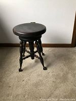 Full view of the piano stool showing three turned legs with claw and ball rolling feet and round spinning seat.