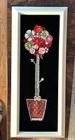First framed jewelry tree with colorful beaded flower topiary in red and silver pot on black velvet background inside a white wood frame.