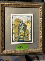 Framed and matted art print with an abstract female figure and decorative motifs, set in a textured gold frame.