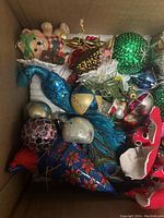 Box with assorted vintage glass mercury Christmas ornaments including figurines, balls, and stars in various colors and finishes.