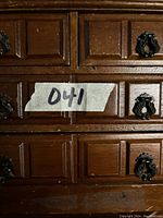 Close-up showing two drawers and their decorative black metal handles on the wooden jewelry box.