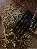 Close-up of gold-tone chain jewelry and black and gold hair combs inside one Ikea drawer.