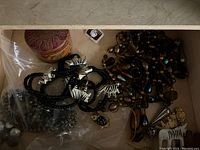 Top view of a wooden drawer with various beaded and wooden jewelry items including a black and white zebra patterned necklace.